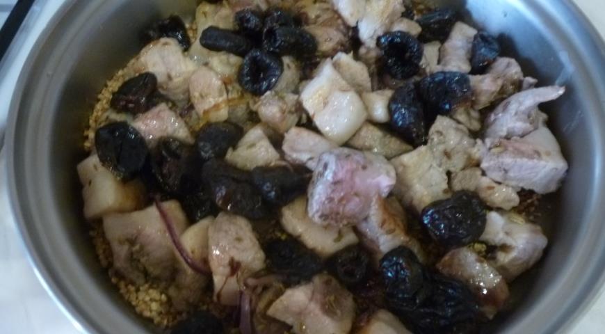 Добавить к мясу гречку, чернослив и бульон, тушить до готовности