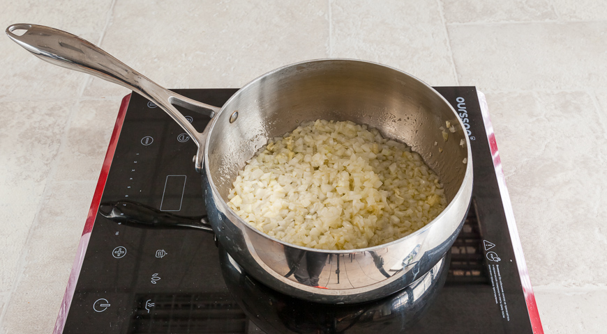 Обжарить рис на оливковом масле, добавив лук и чеснок
