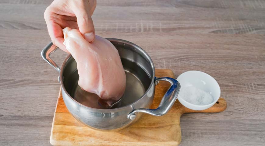 Положите куриную грудку для слоеного салата в кастрюлю