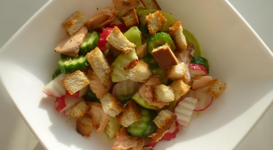 Добавляем кусочки рыбы и сухарики, салат из запеченной семги готов